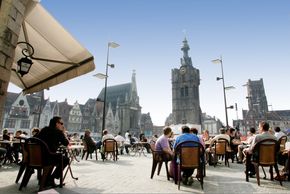 Des gens sont assis à la terrasse d'un café sur la Grand'Place de Béthune. 