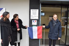 trois personnes qui dévoilent une plaque, cachée sous un drapeau tricolore