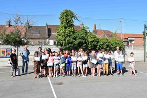 Des enfants posent dans une cour d'école avec un diplôme.