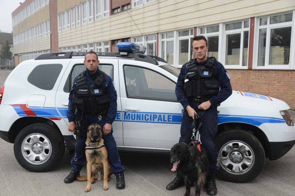 Les agents de la police municipale avec deux chiens à leurs pieds.